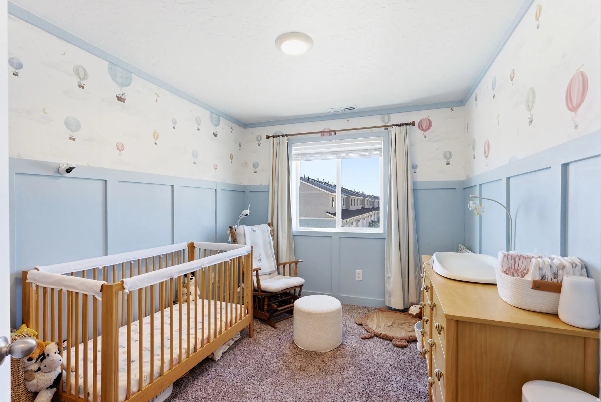 Room featuring wainscoting and crown molding, light blue wall accents, and a window with white trim