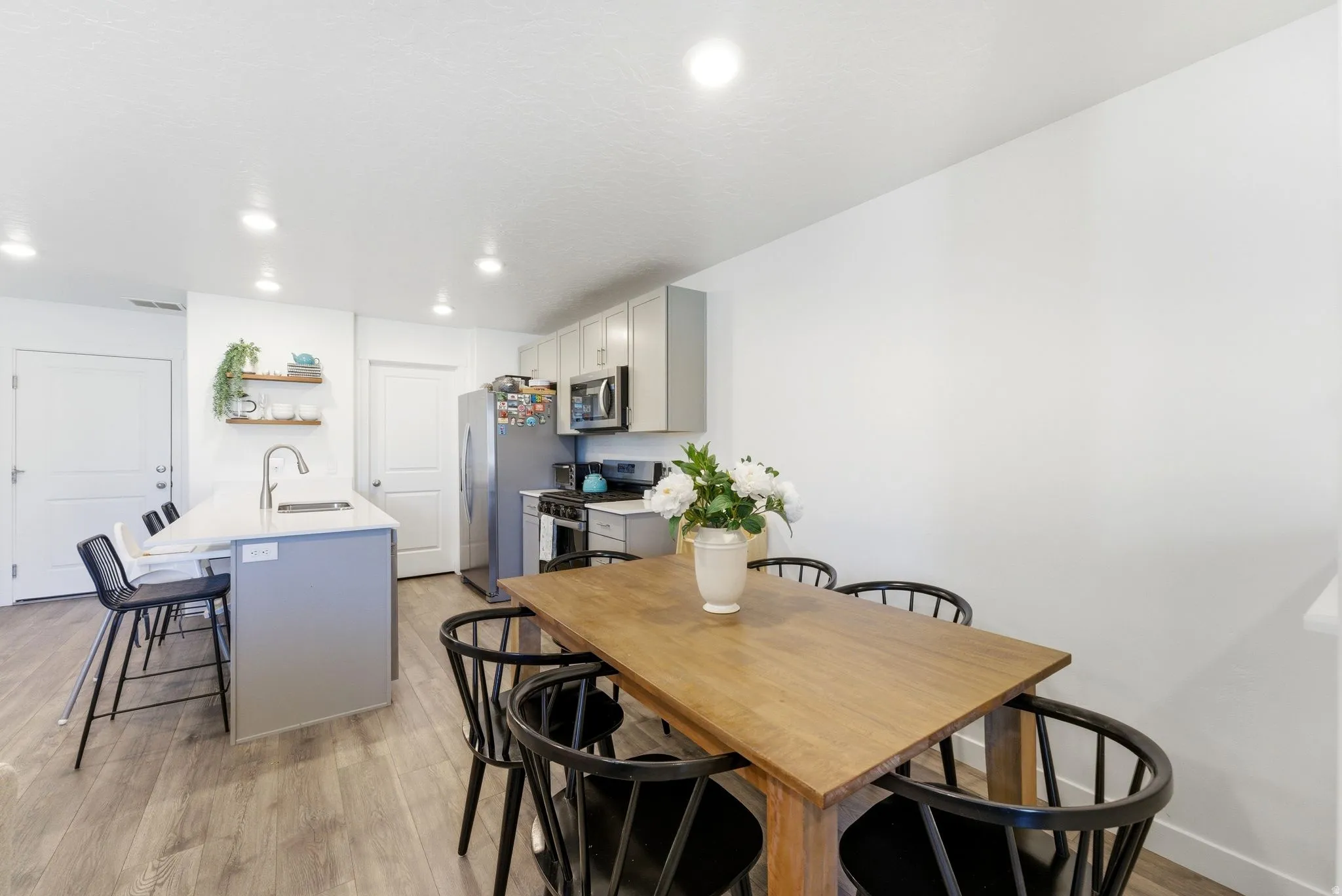 Bright kitchen featuring light wood-finish flooring, white walls, recessed lighting, and a kitchen island with seating