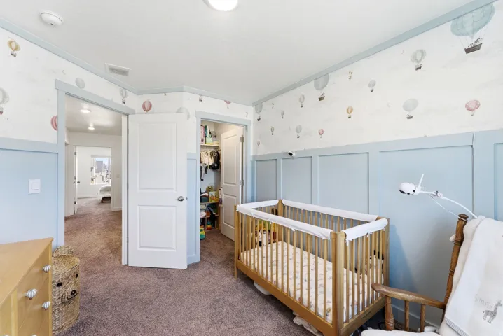 Interior room featuring wall paneling, patterned wallpaper, a built-in closet with double panel door, and plush carpet flooring