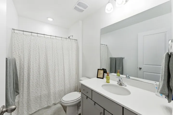 White vanity with integrated sink, chrome faucet, and expansive mirror