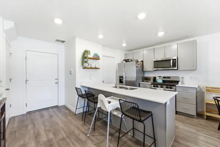 Modern kitchen featuring light gray cabinetry, stainless steel appliances, and a central island with an integrated sink