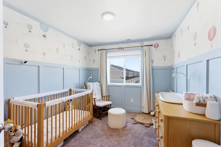 Room featuring wainscoting and crown molding, light blue wall accents, and a window with white trim
