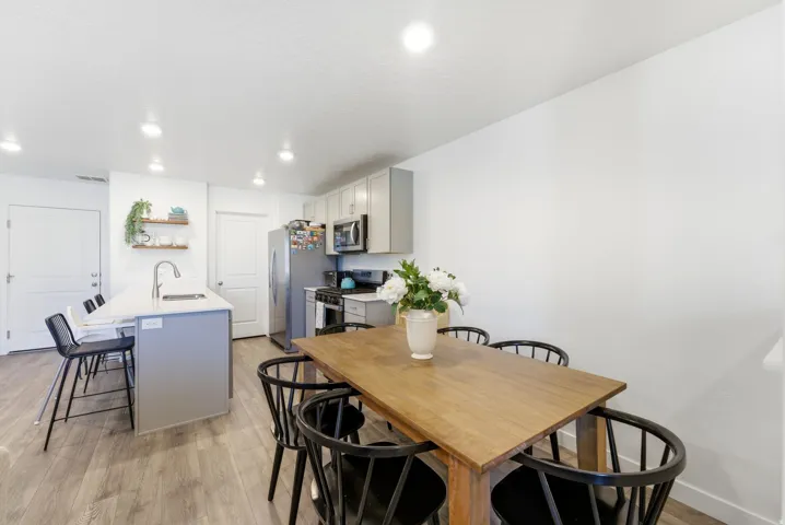 Bright kitchen featuring light wood-finish flooring, white walls, recessed lighting, and a kitchen island with seating