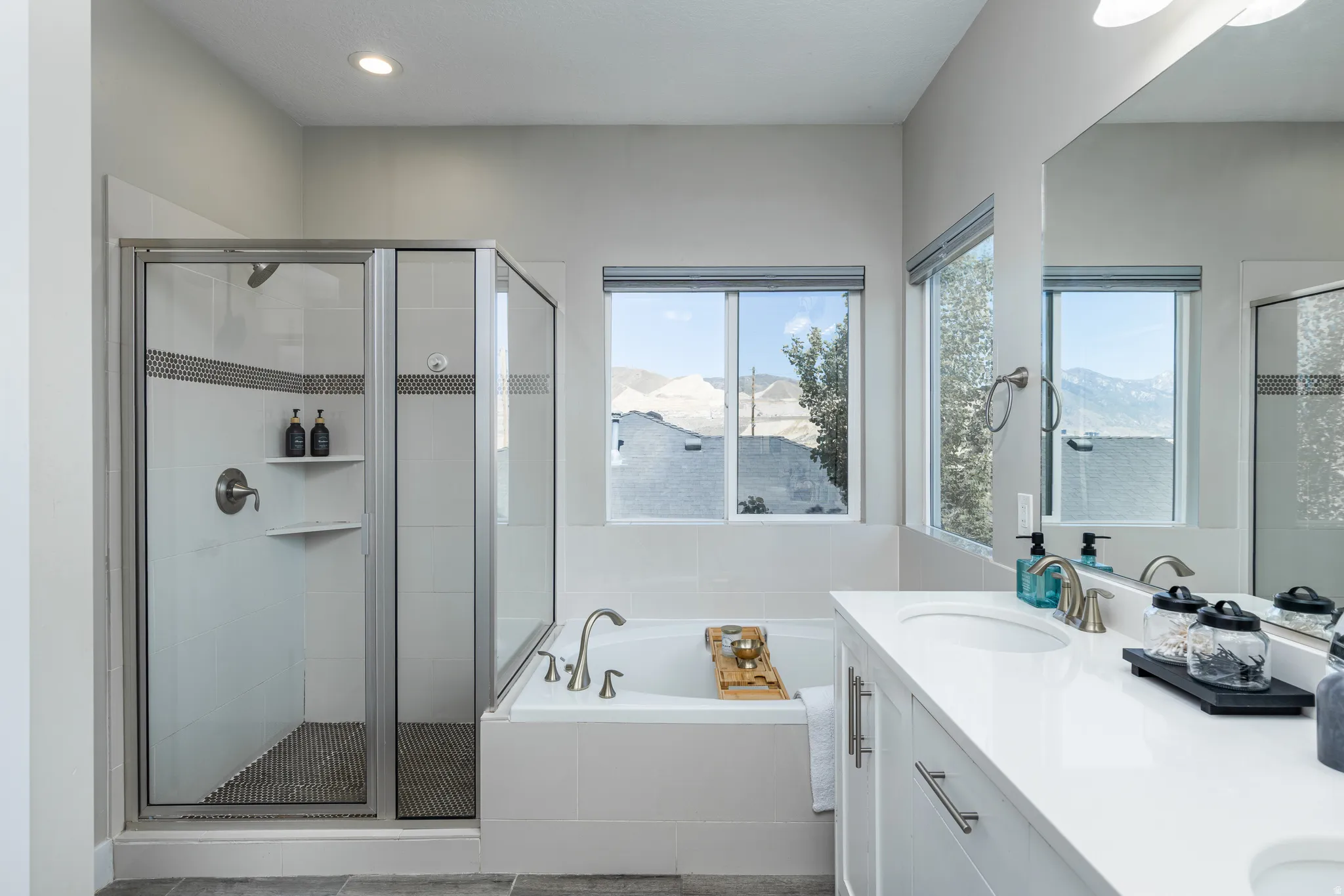 Contemporary bathroom featuring a white soaking tub with deck-mounted faucet and a glass-enclosed shower with tiled walls and a mosaic floor