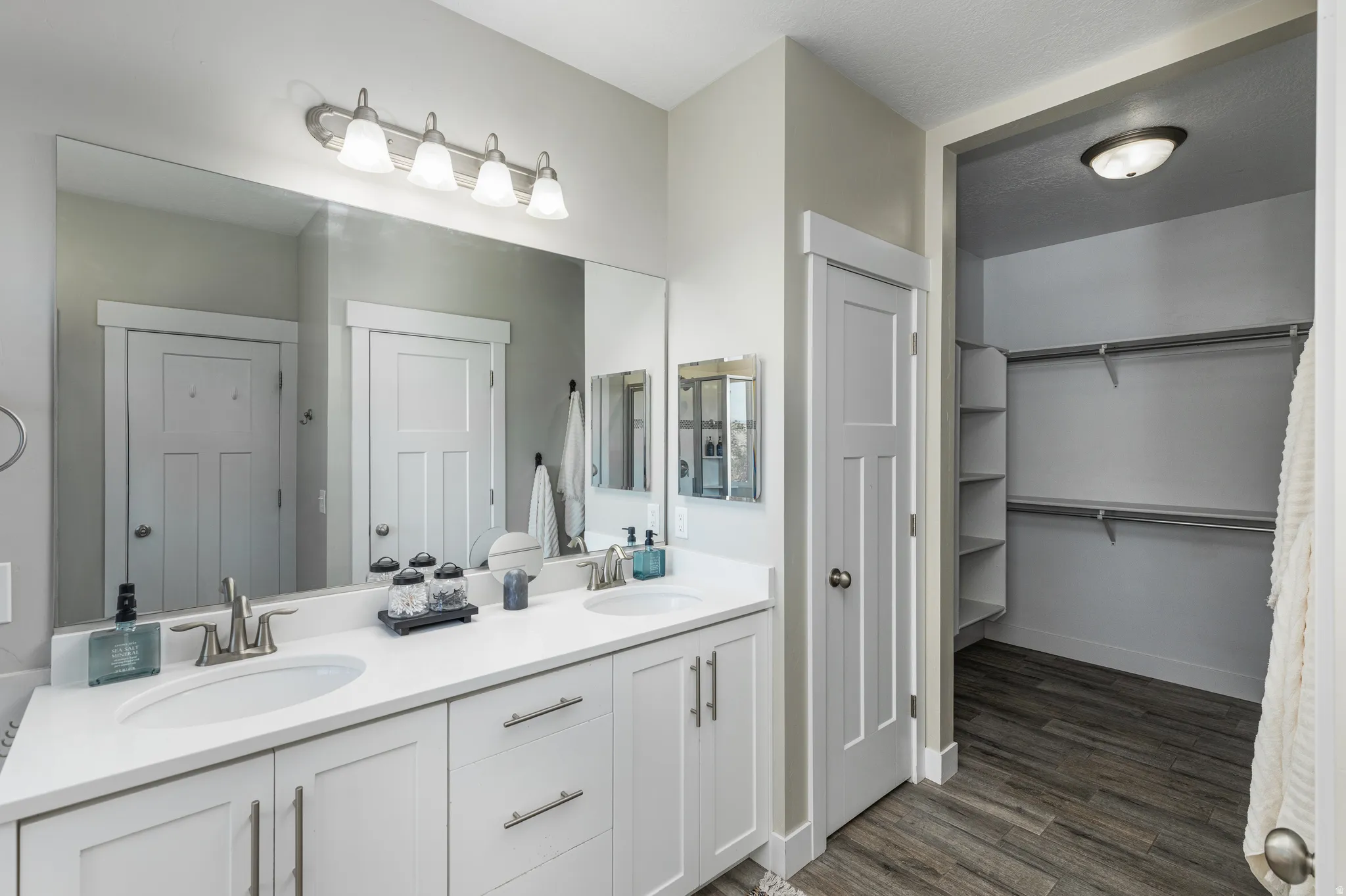 Double vanity featuring white cabinetry, undermount sinks, and a large wall-mounted mirror
