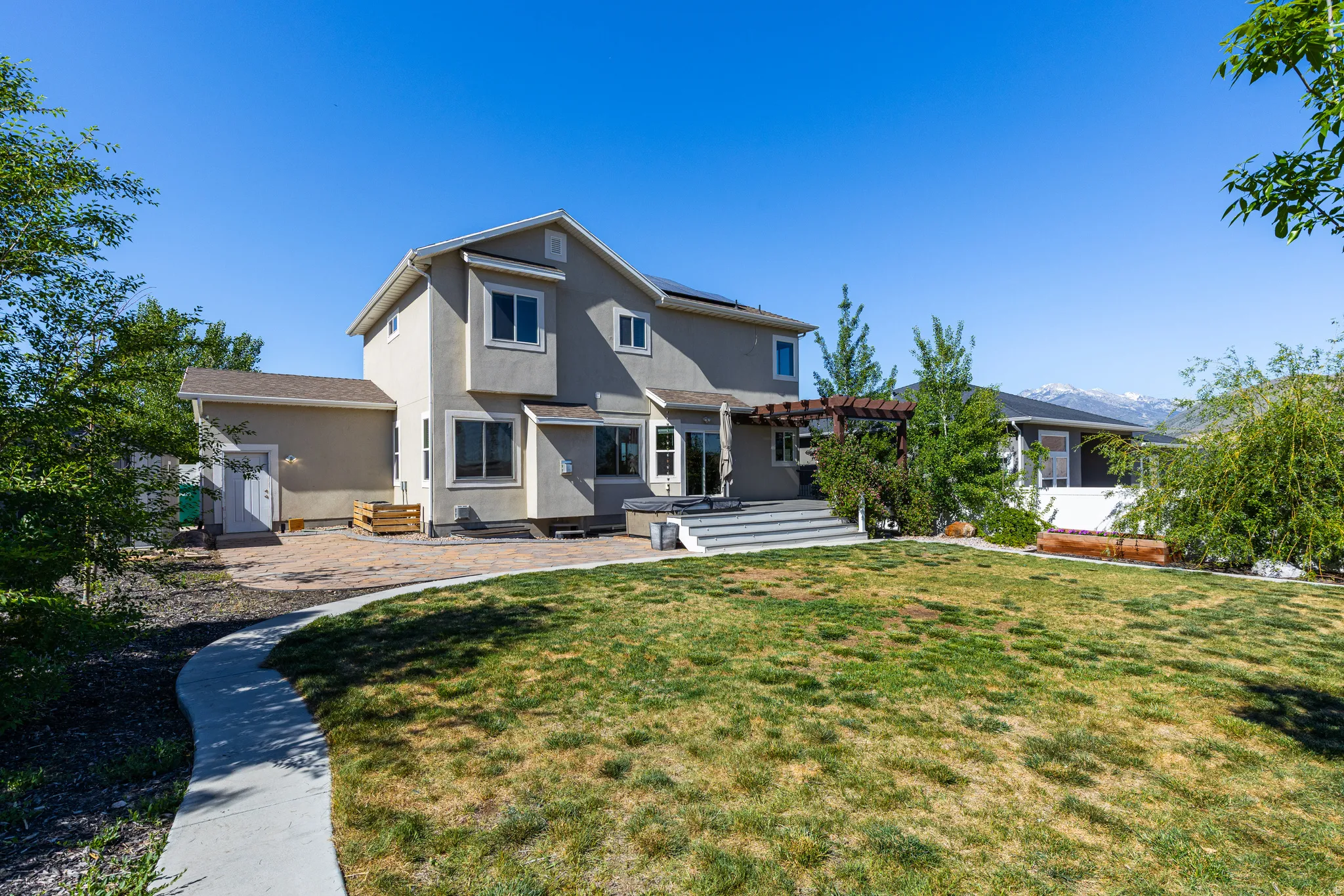 Spacious backyard featuring a multi-level deck with pergola, extensive patio area, and a concrete pathway