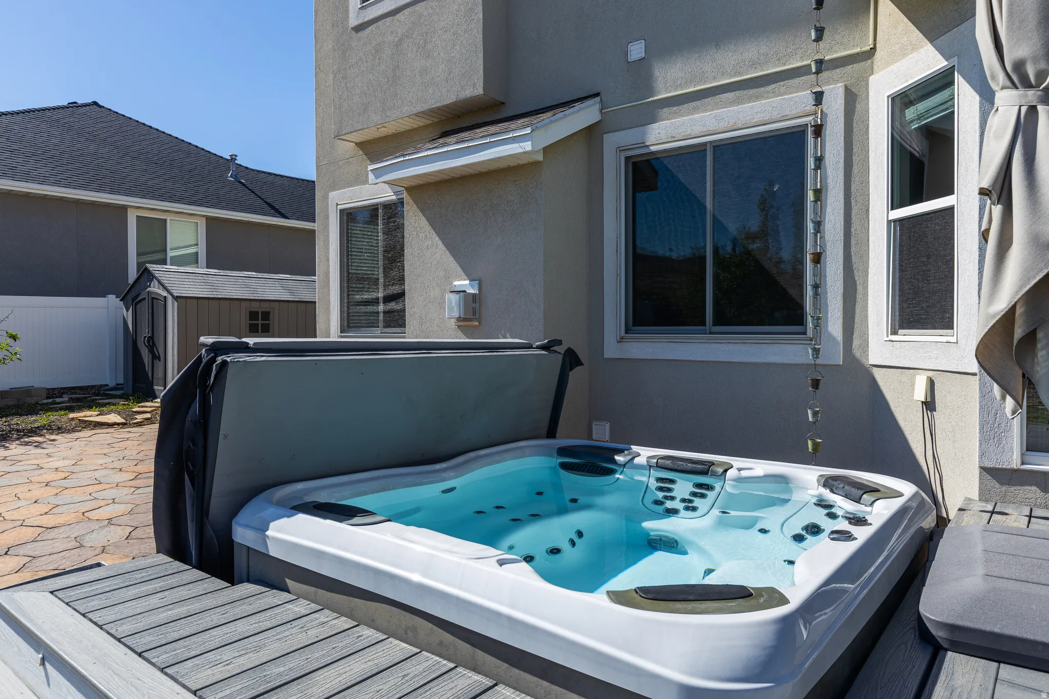 Outdoor spa featuring multiple jets, integrated seating, a protective cover, and composite decking surround