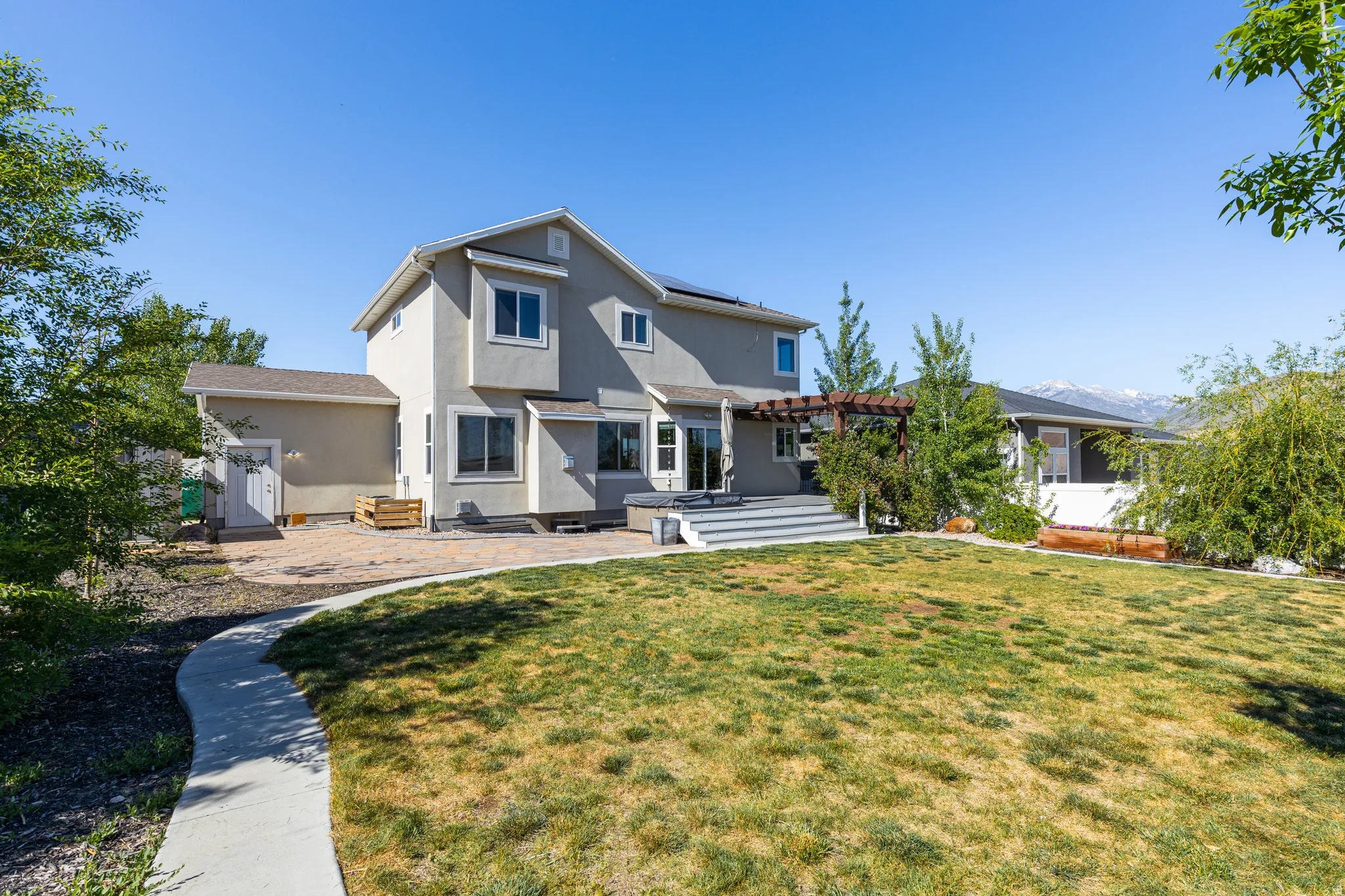 HOT TUB- Deck, Garden box, Expansive backyard featuring a concrete pathway, a manicured lawn, and mature trees