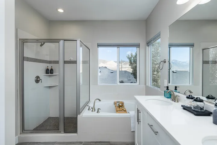 Contemporary bathroom featuring a white soaking tub with deck-mounted faucet and a glass-enclosed shower with tiled walls and a mosaic floor
