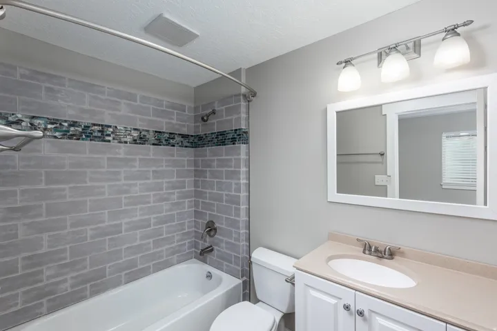 Bathroom featuring a white vanity with a light-toned countertop, an oval undermount sink, and brushed nickel fixtures