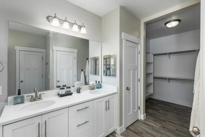 Double vanity featuring white cabinetry, undermount sinks, and a large wall-mounted mirror