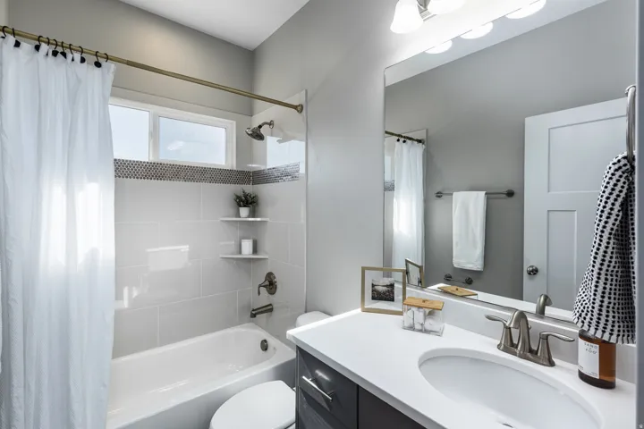 Bathroom featuring a built-in tub with a tile surround, window, and corner shelving