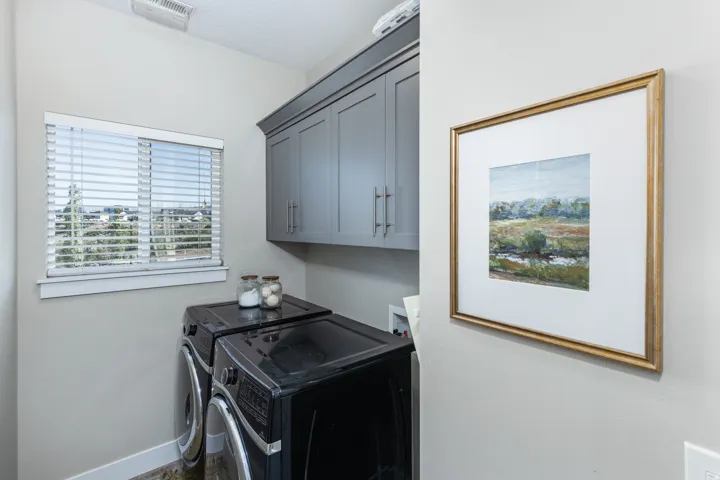 Laundry area featuring upper cabinetry with brushed nickel hardware, light neutral wall paint, and a window with blinds