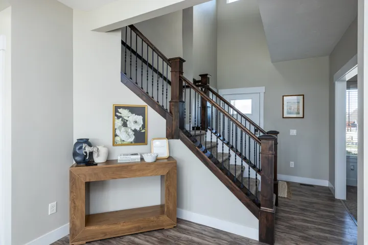 Two-story entry featuring wood-finish flooring, a grand staircase with dark wood newel posts and black wrought iron balusters, and a high ceiling with transom windows