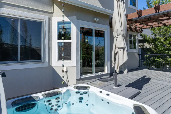 Outdoor deck featuring a built-in spa, composite decking, and a sliding glass door