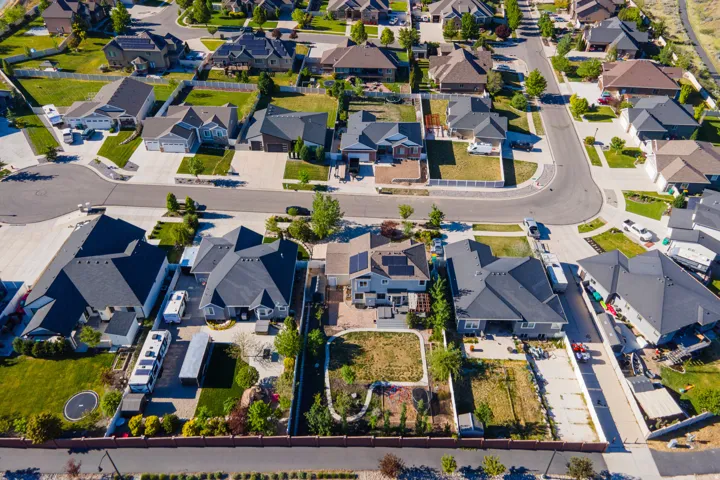 Aerial view of a residential community with asphalt streets and manicured lawns