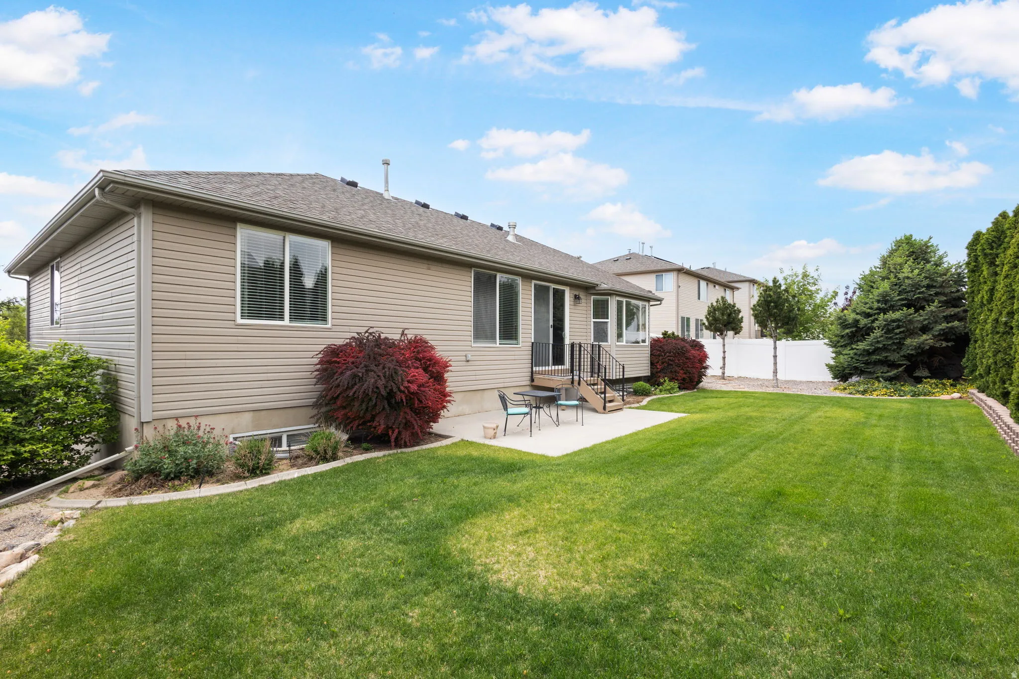 Expansive backyard lined with trees for complete privacy, featuring a manicured lawn, concrete patio, mature trees, and privacy fencing