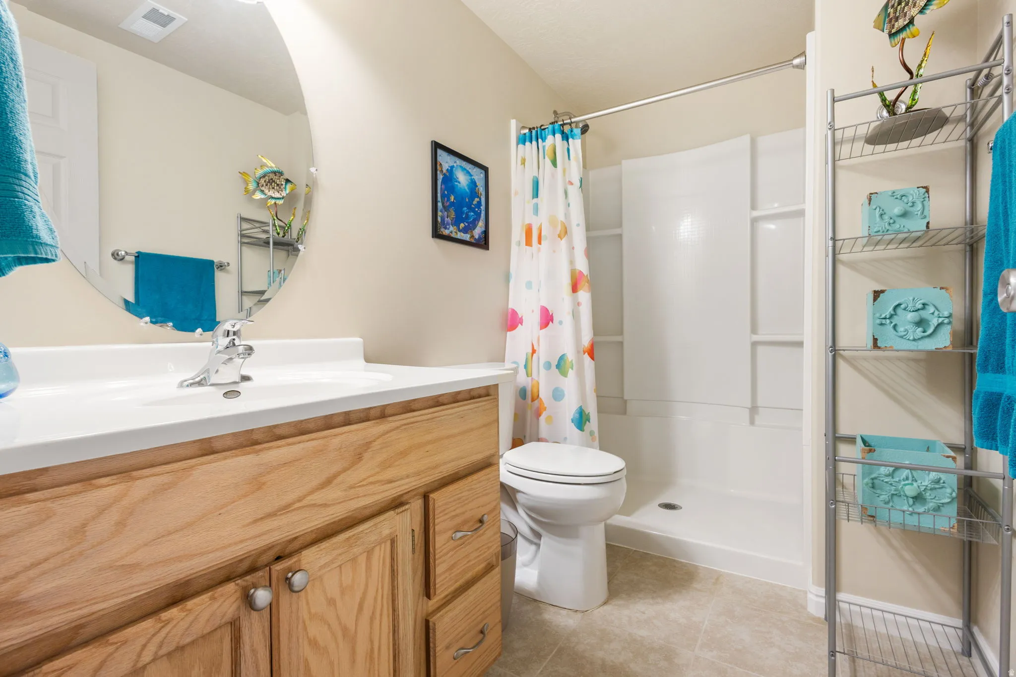 Bathroom featuring a light wood-finish vanity with an integrated sink, polished chrome faucet, and a large oval mirror