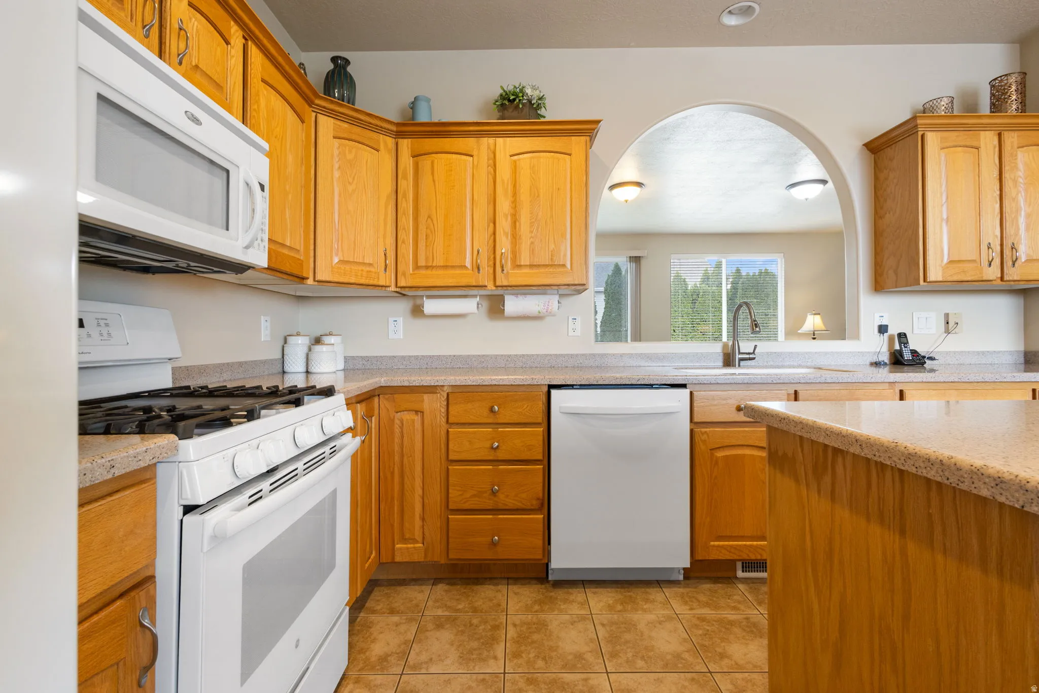 Kitchen featuring abundant wood cabinetry, light-toned countertops, and tile flooring