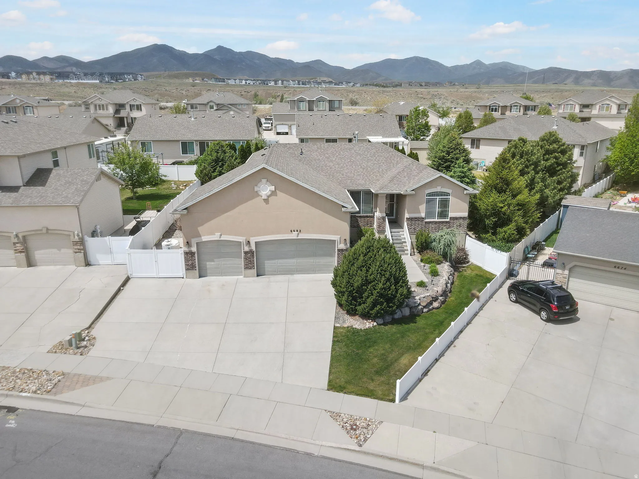 Two-story residence featuring a two-car garage with stone accents, a landscaped front yard with mature shrubbery, and a concrete driveway
