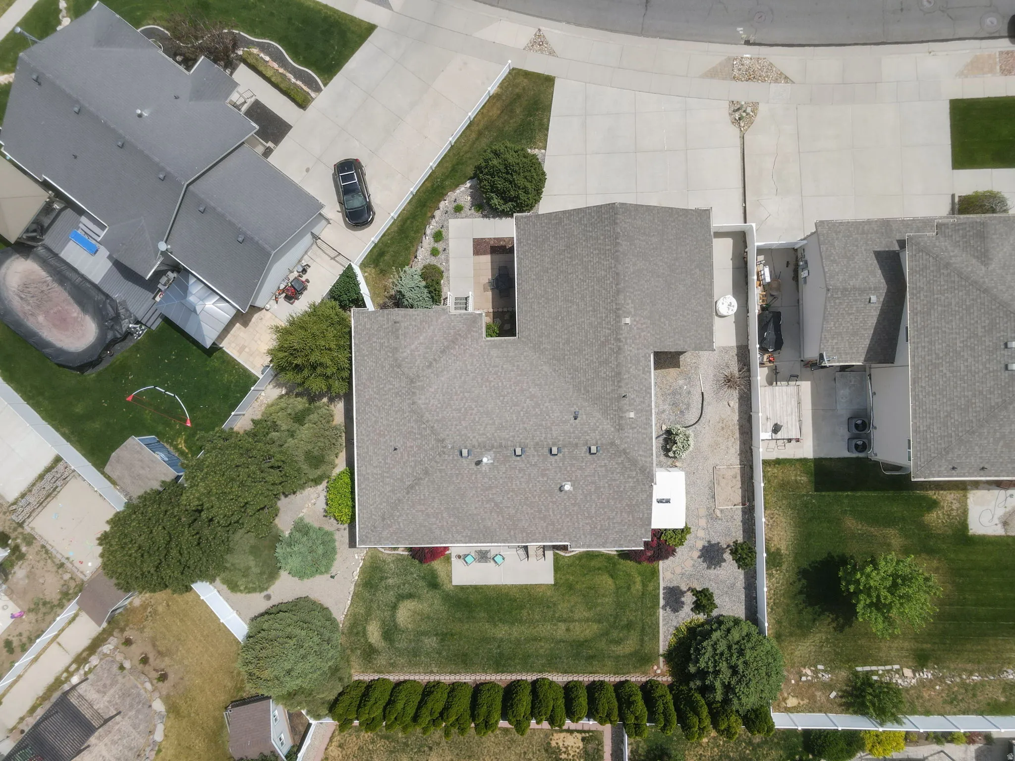 Expansive property featuring a grey shingle roof, concrete driveway, and a backyard with a manicured lawn