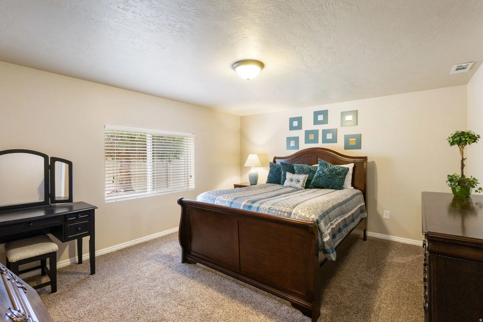 Carpeted room featuring a window with horizontal blinds, a ceiling-mounted light fixture, and light-toned wall finishes