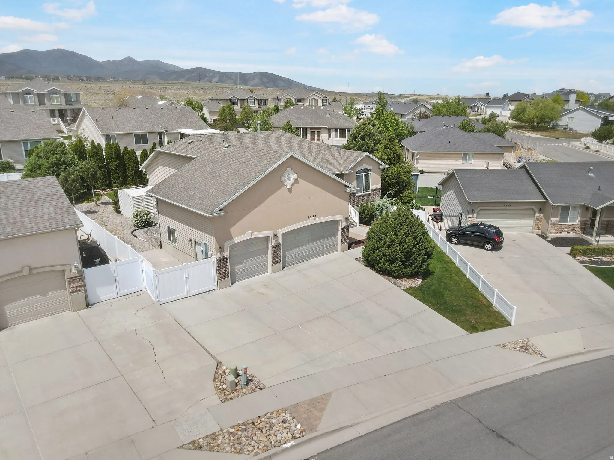 Stucco exterior residence featuring a two-car garage, concrete driveway, and white privacy fencing