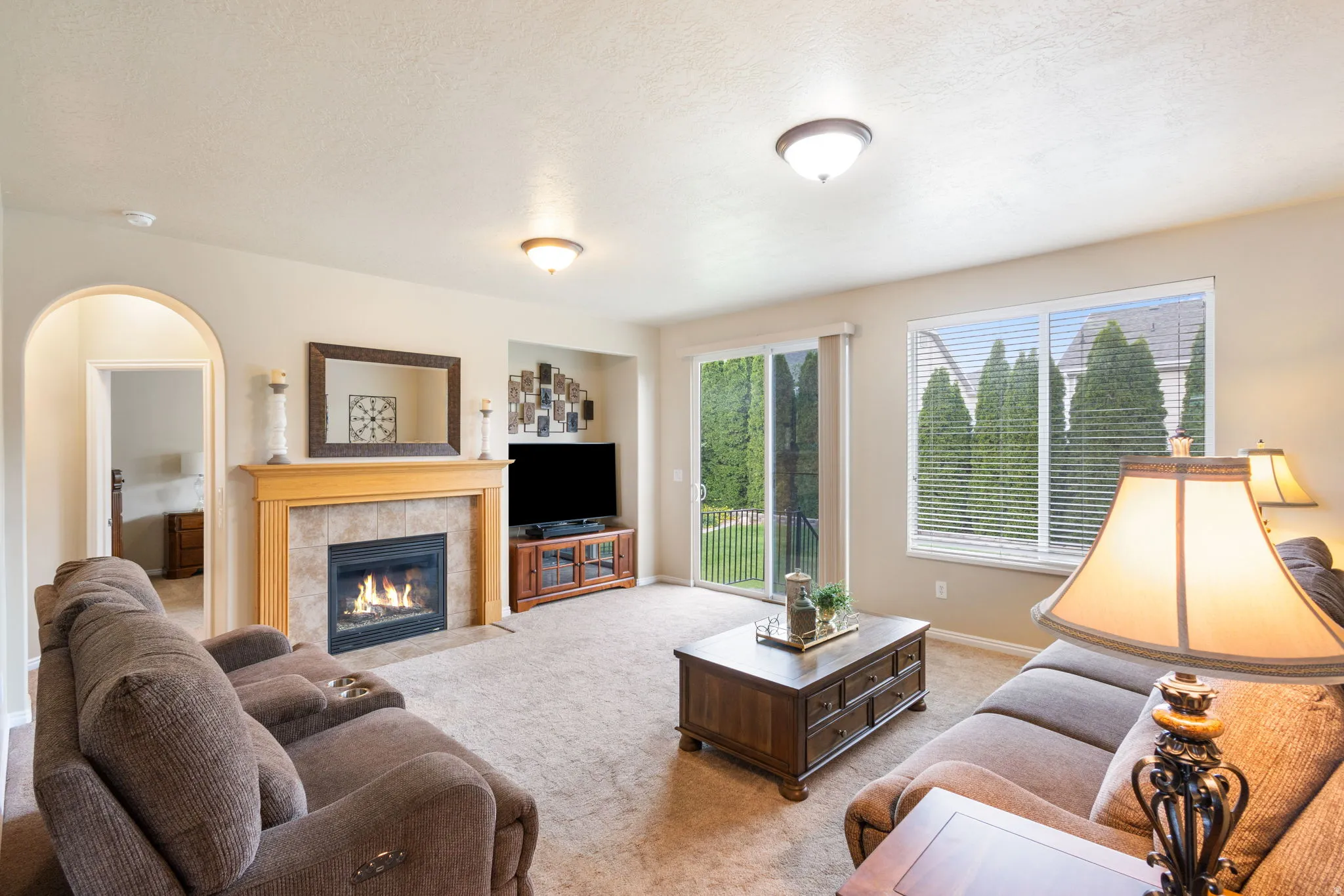 Living area featuring a gas fireplace with a tile surround and wood mantel, large sliding glass door, and an arched doorway