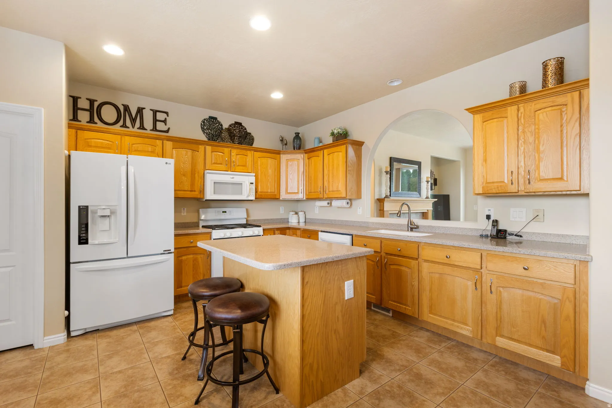 Kitchen featuring light wood cabinetry, stone-finish countertops, and tile flooring