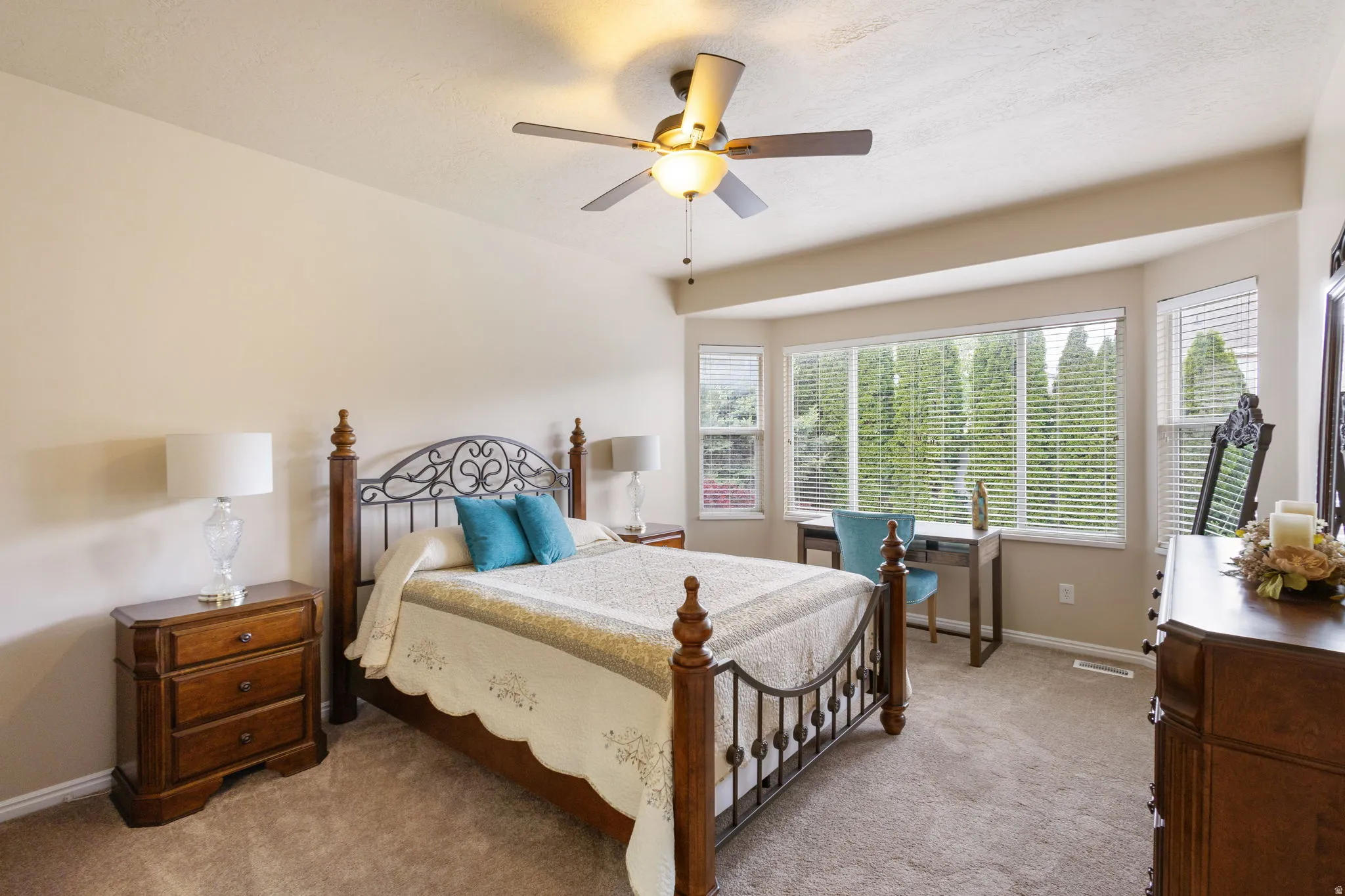 Large primary bedroom with a bay window, ceiling fan, and window blinds