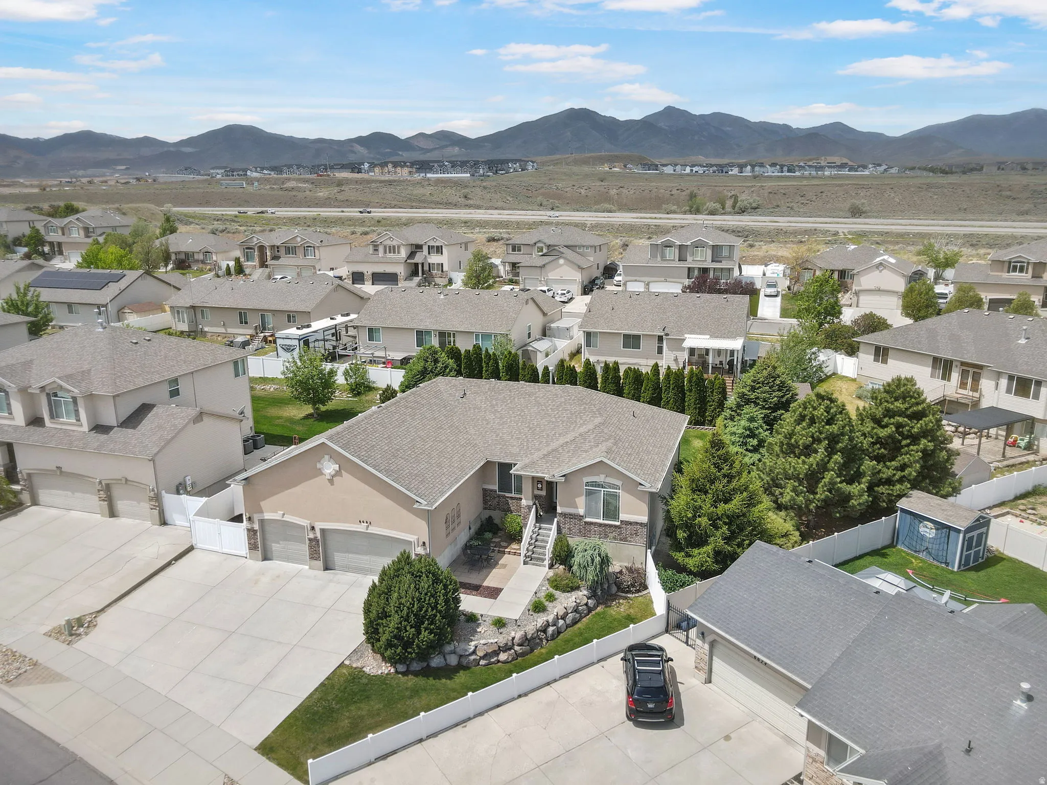 Ranch-style residence featuring a multi-car driveway, two-car garage, manicured landscaping, and a fenced perimeter