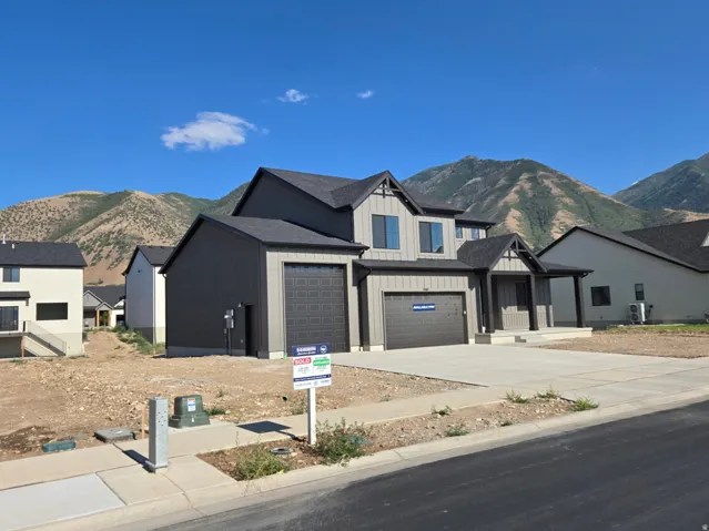 Contemporary two-story residence featuring a dark gray and light gray exterior, a two-car garage with textured doors, and a covered front entry