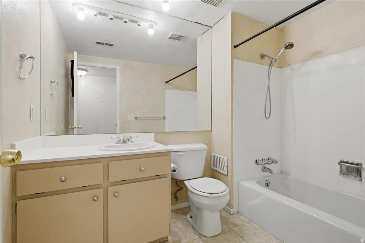 Bathroom featuring a vanity with an integrated sink, track lighting, and a combination tub and shower with a handheld showerhead