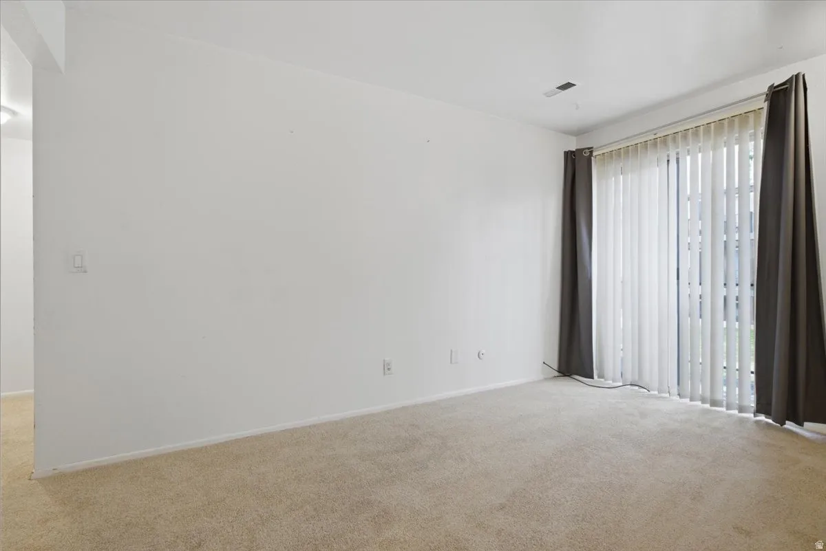 Neutral-toned carpeting, white wall finishes, and vertical blinds