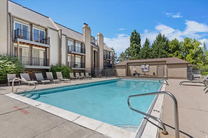 Outdoor swimming pool with concrete decking, surrounded by a metal fence