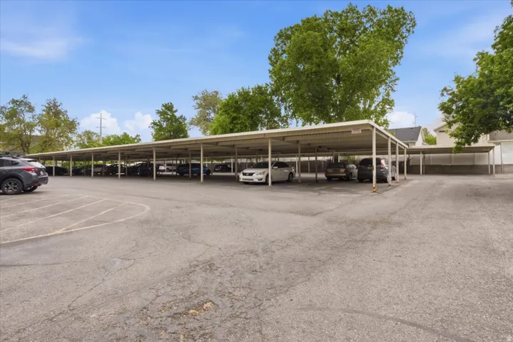Extensive covered parking structure featuring multiple bays, a paved lot, and mature trees providing natural screening