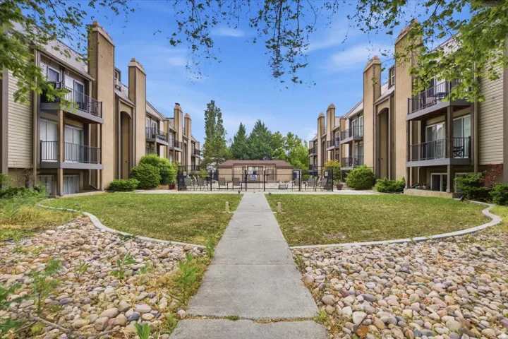 Symmetrical multi-story building exteriors featuring balconies with black railings, tan siding, and integrated chimneys