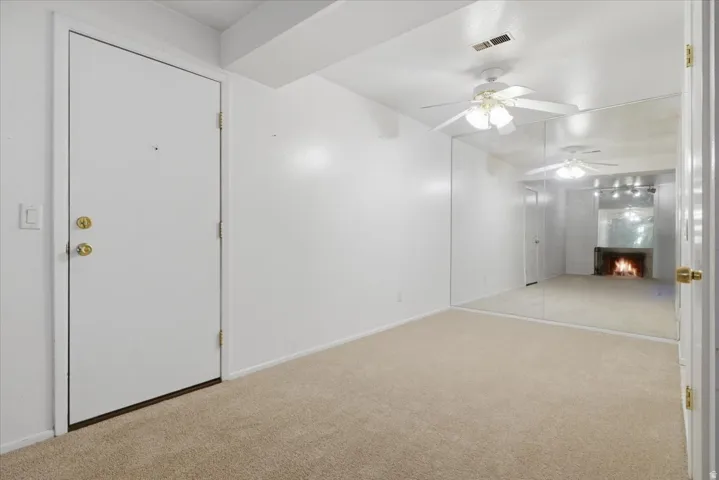 Entryway with neutral carpet flooring and a ceiling fan