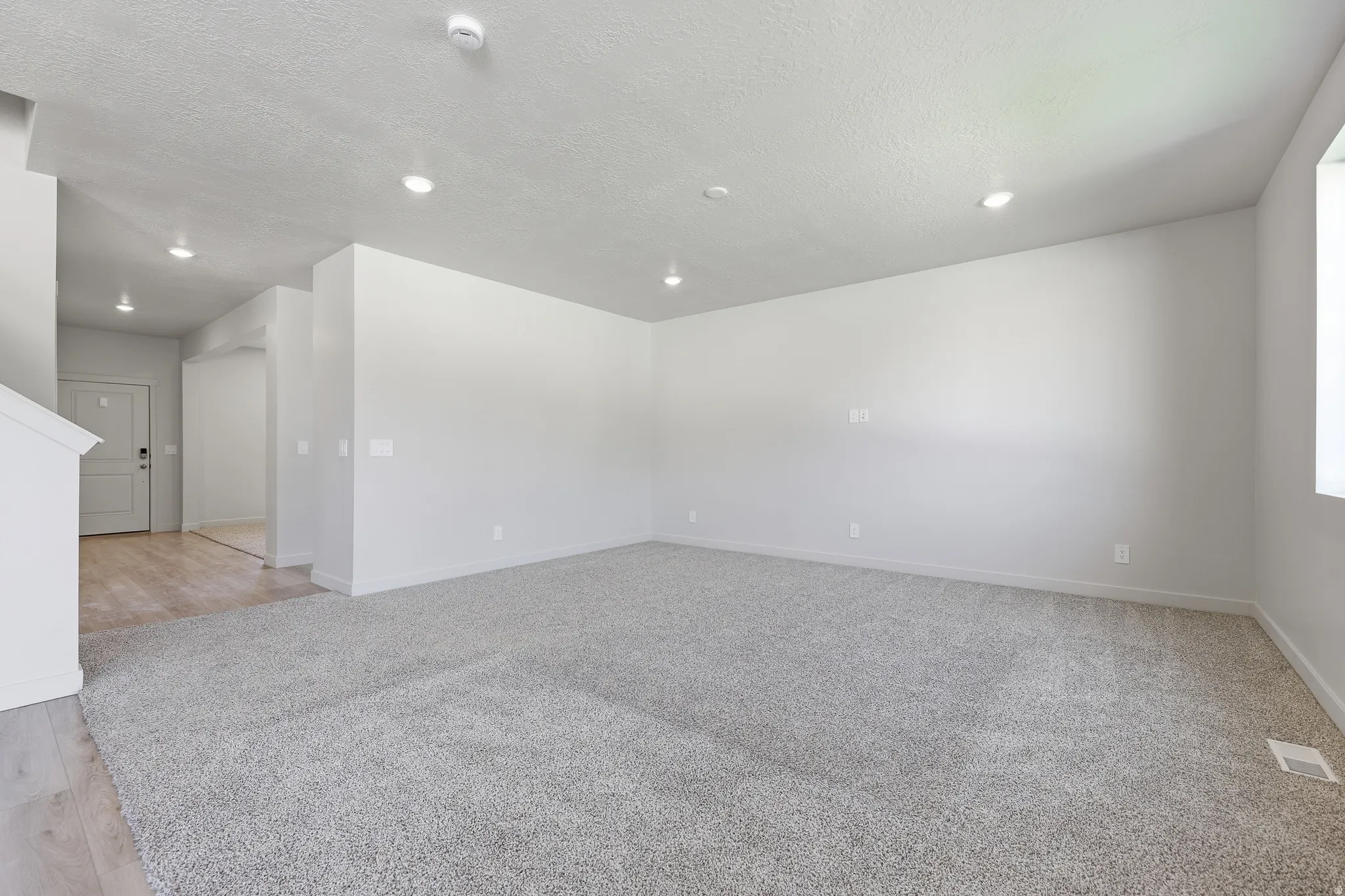 Spacious room with light gray carpeting, recessed ceiling lighting, and a neutral wall finish