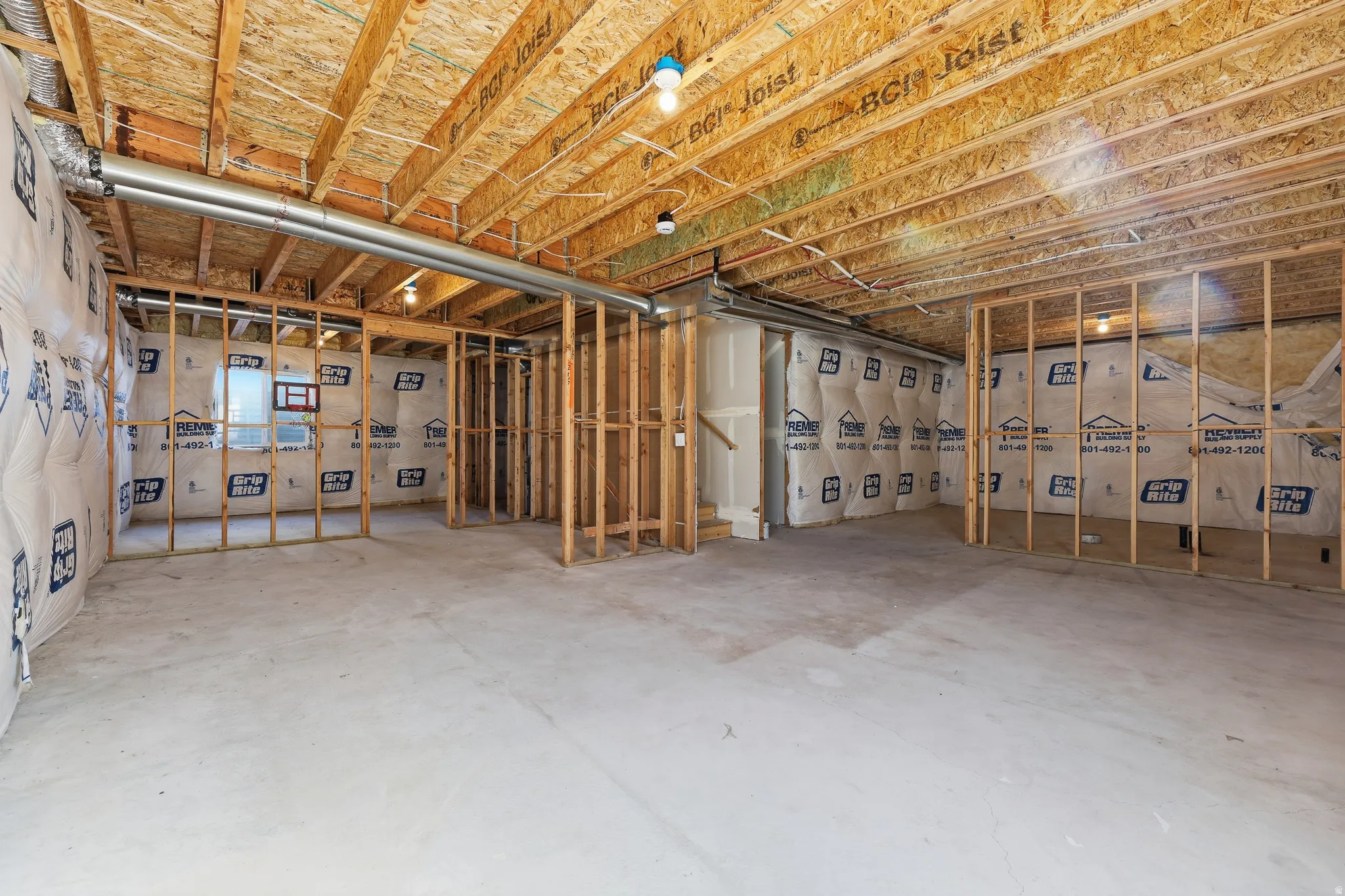 Unfinished basement with exposed ceiling joists, wood framing, concrete flooring, and insulated exterior walls