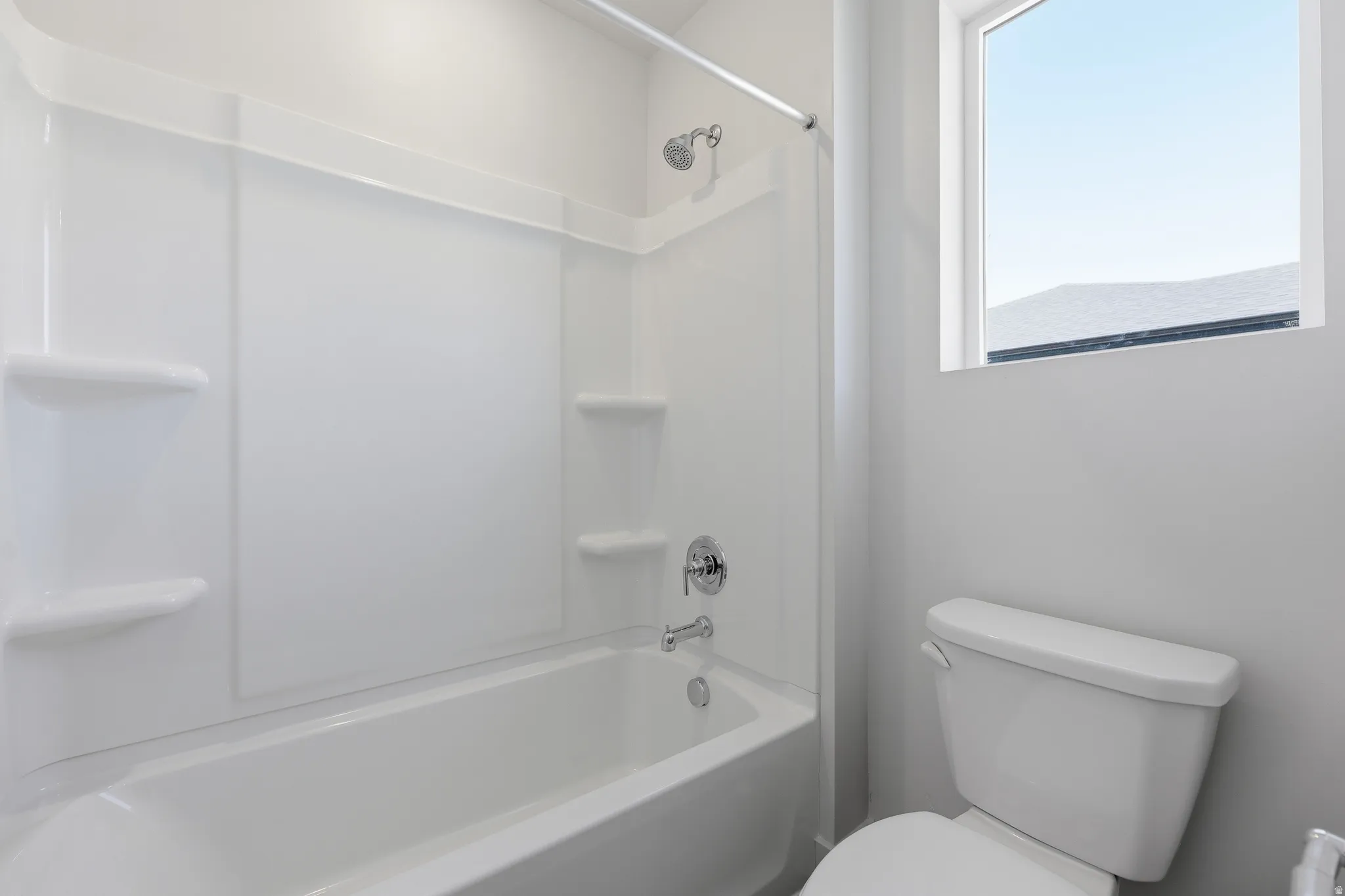 Bathtub and shower combination with white surround, chrome fixtures, and built-in shelving