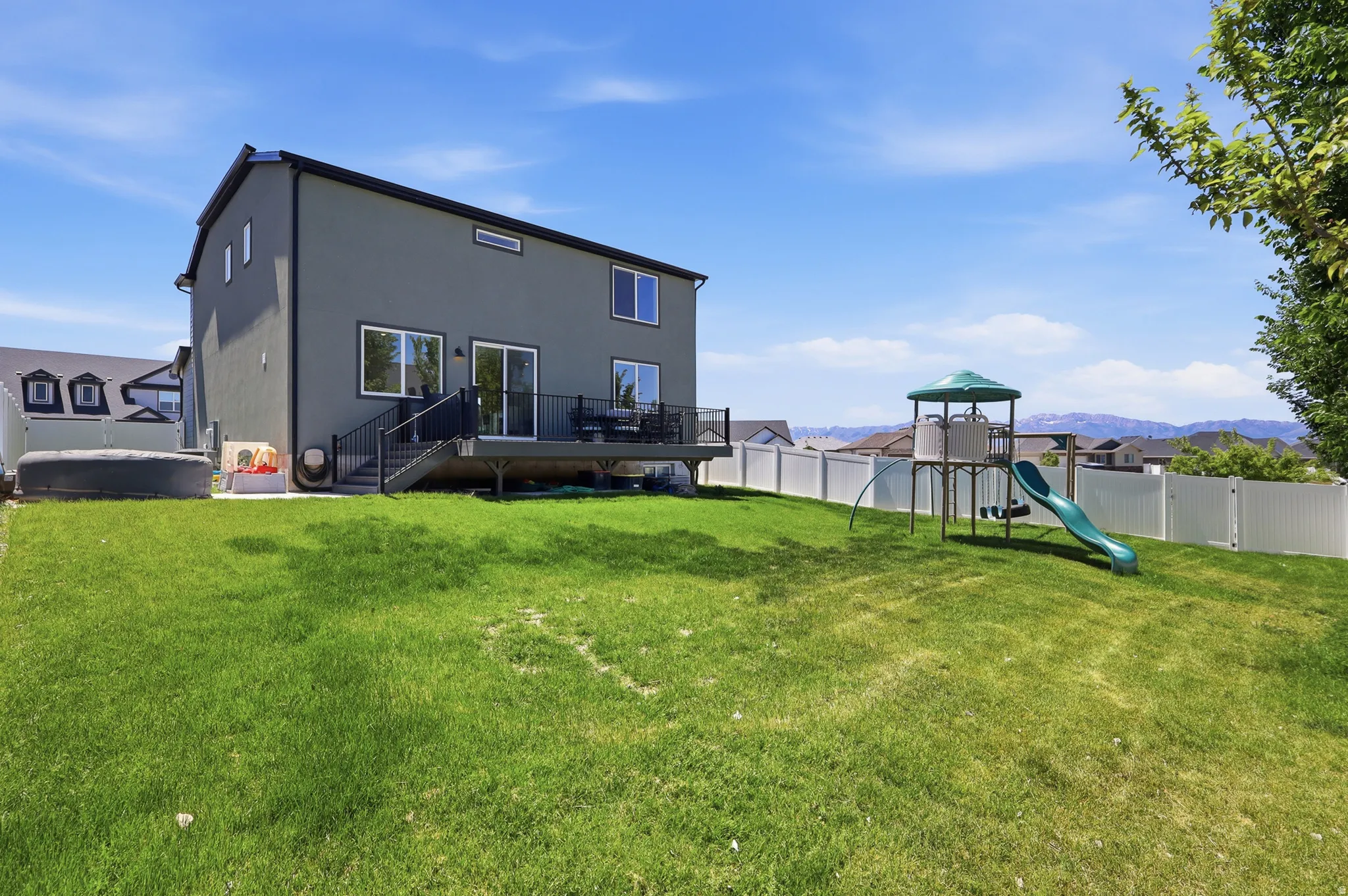 Expansive backyard featuring a green lawn, a privacy fence, and distant mountain scenery