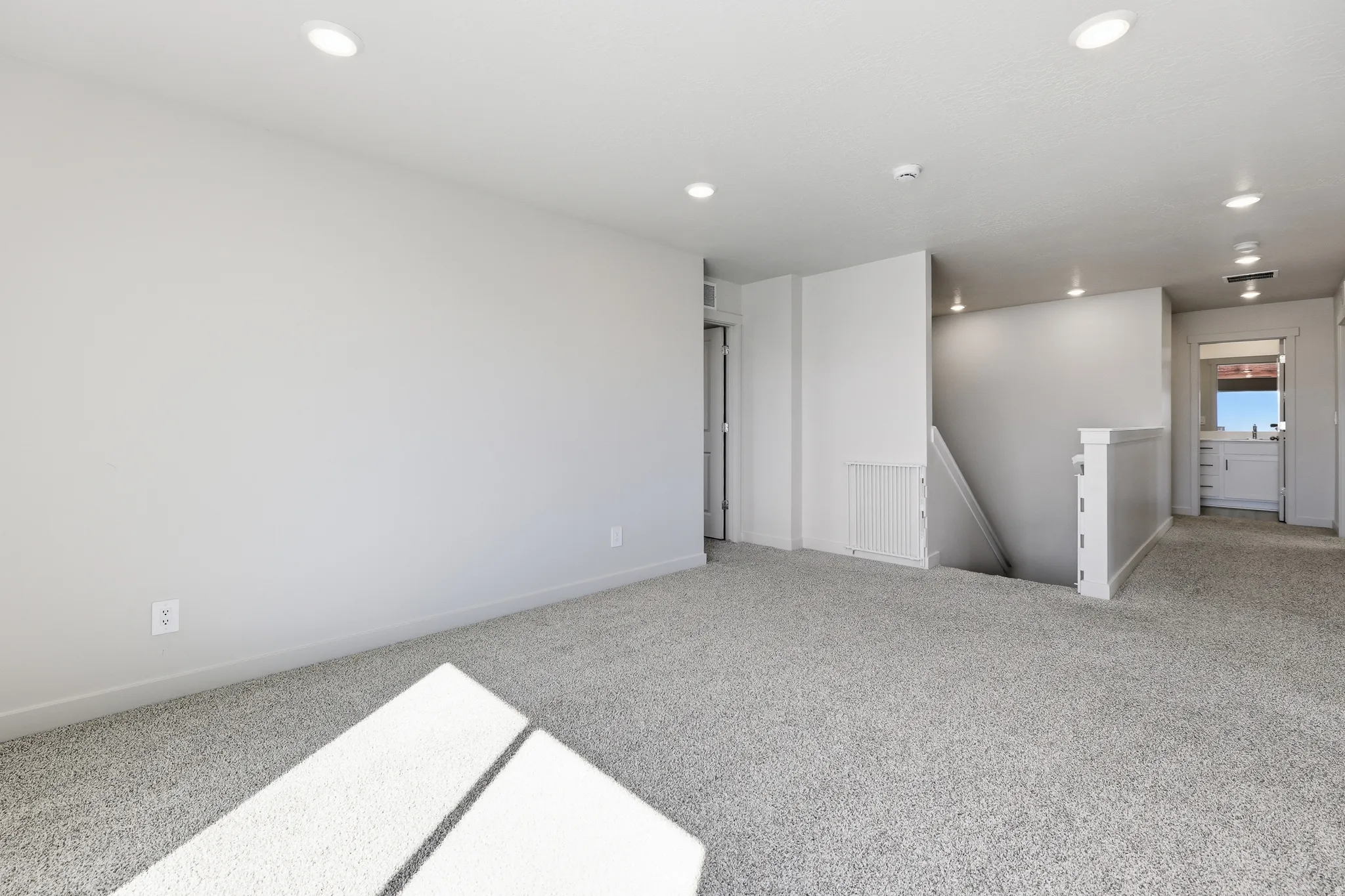 Spacious room with gray carpet flooring and recessed lighting