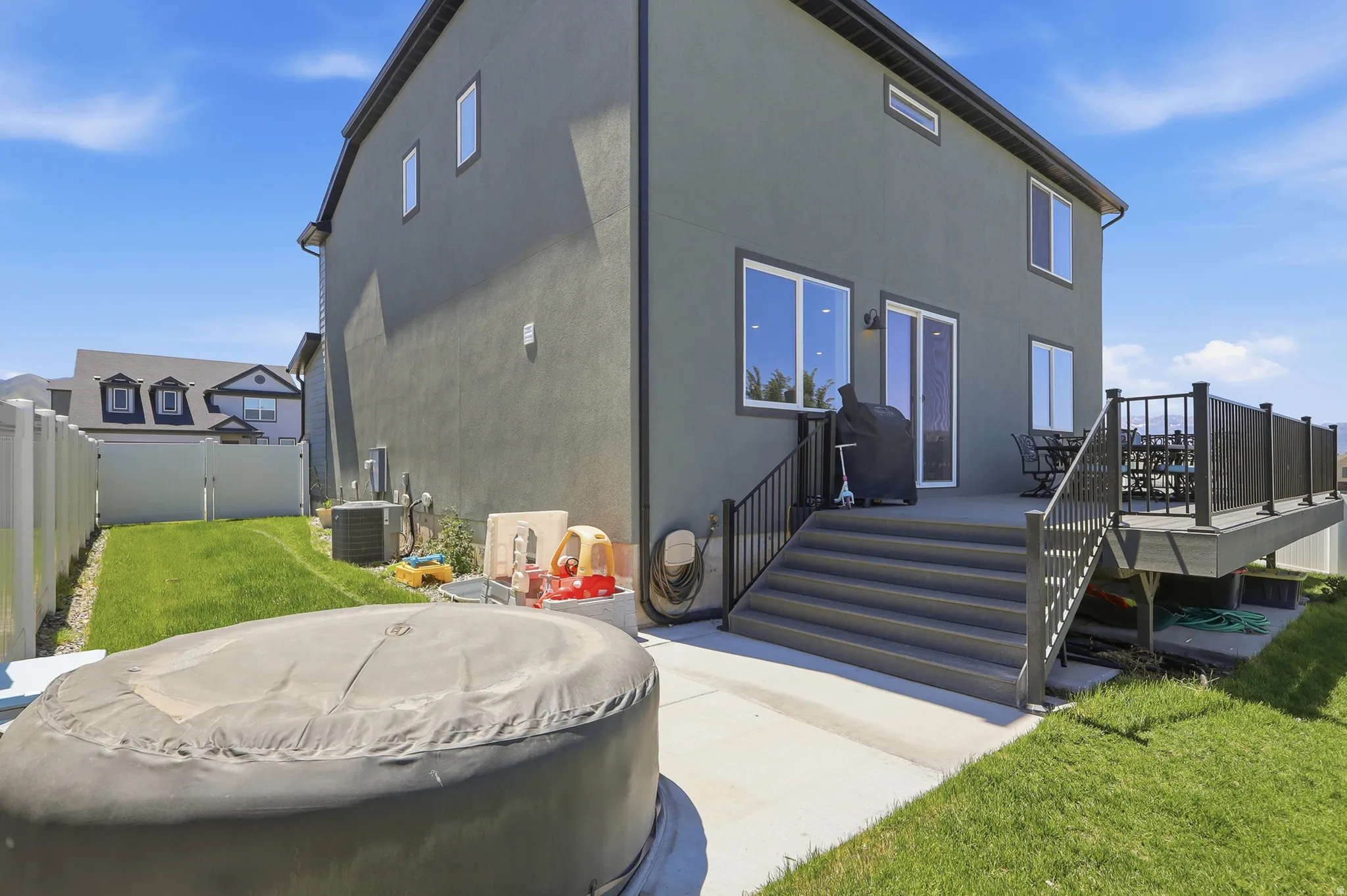 Rear exterior featuring a multi-level deck with black railings, stucco siding, and multiple windows