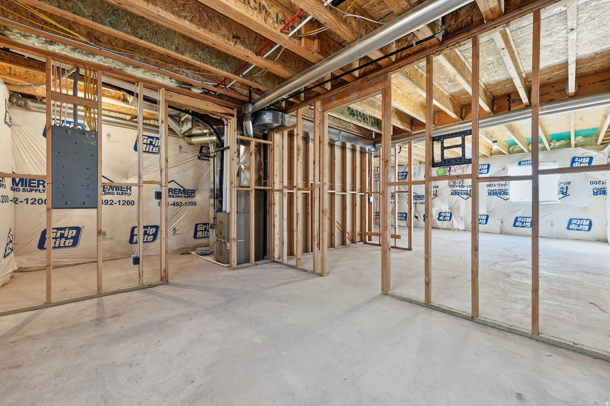Unfinished basement with exposed wood framing, concrete flooring, visible insulation, and ductwork