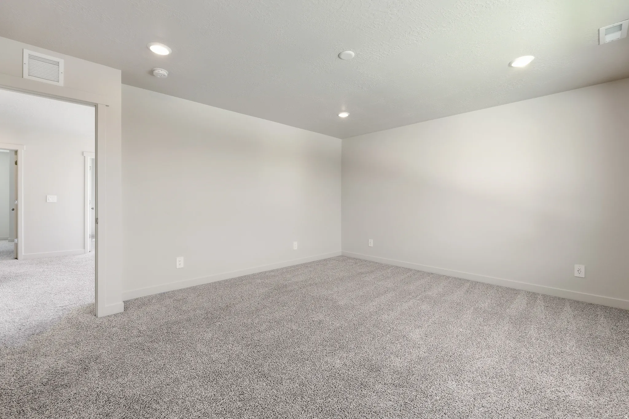 Spacious room featuring neutral carpeting, light gray wall paint, and recessed ceiling lighting