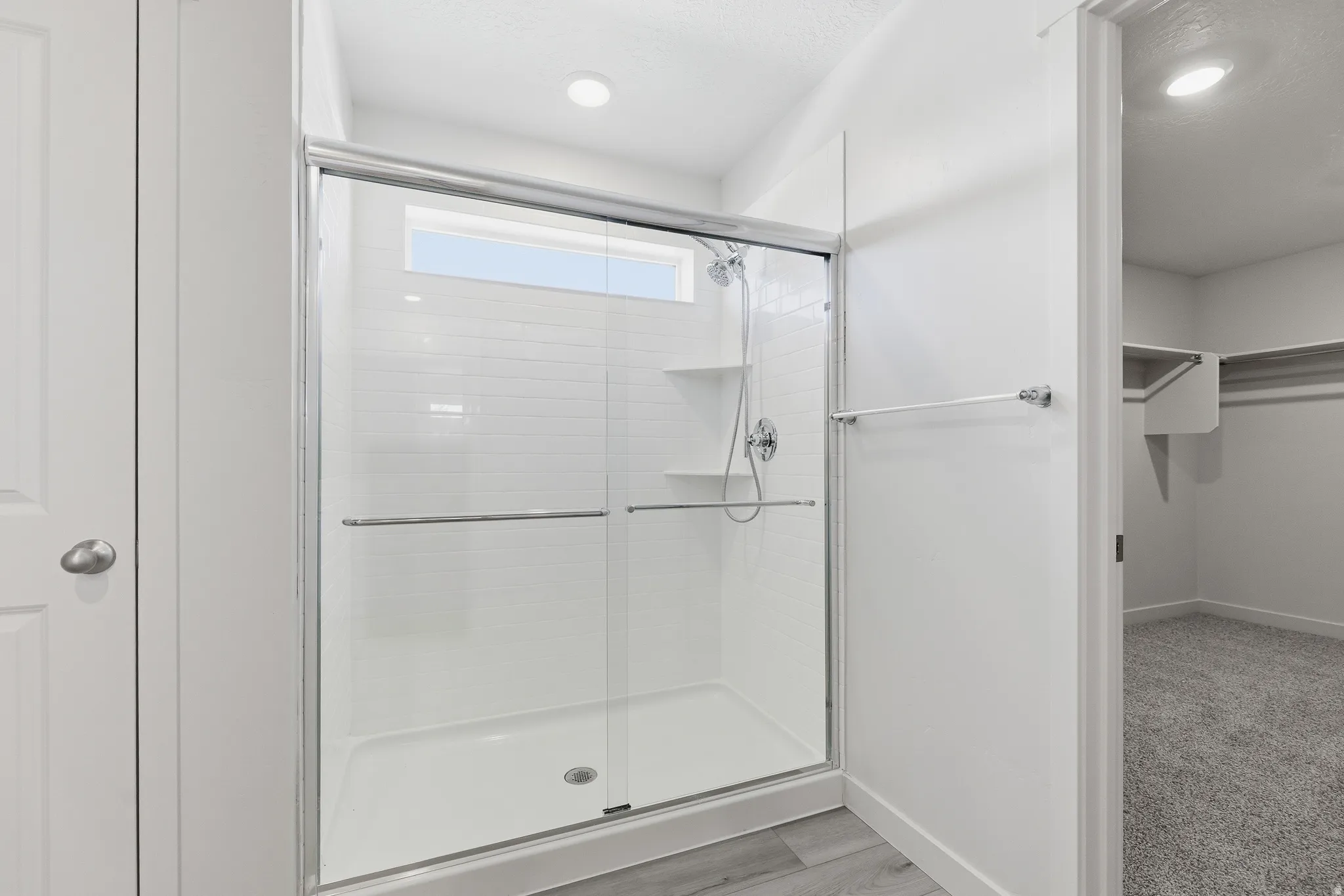 Shower enclosure with subway tile surround, integrated shelving, and a transom window