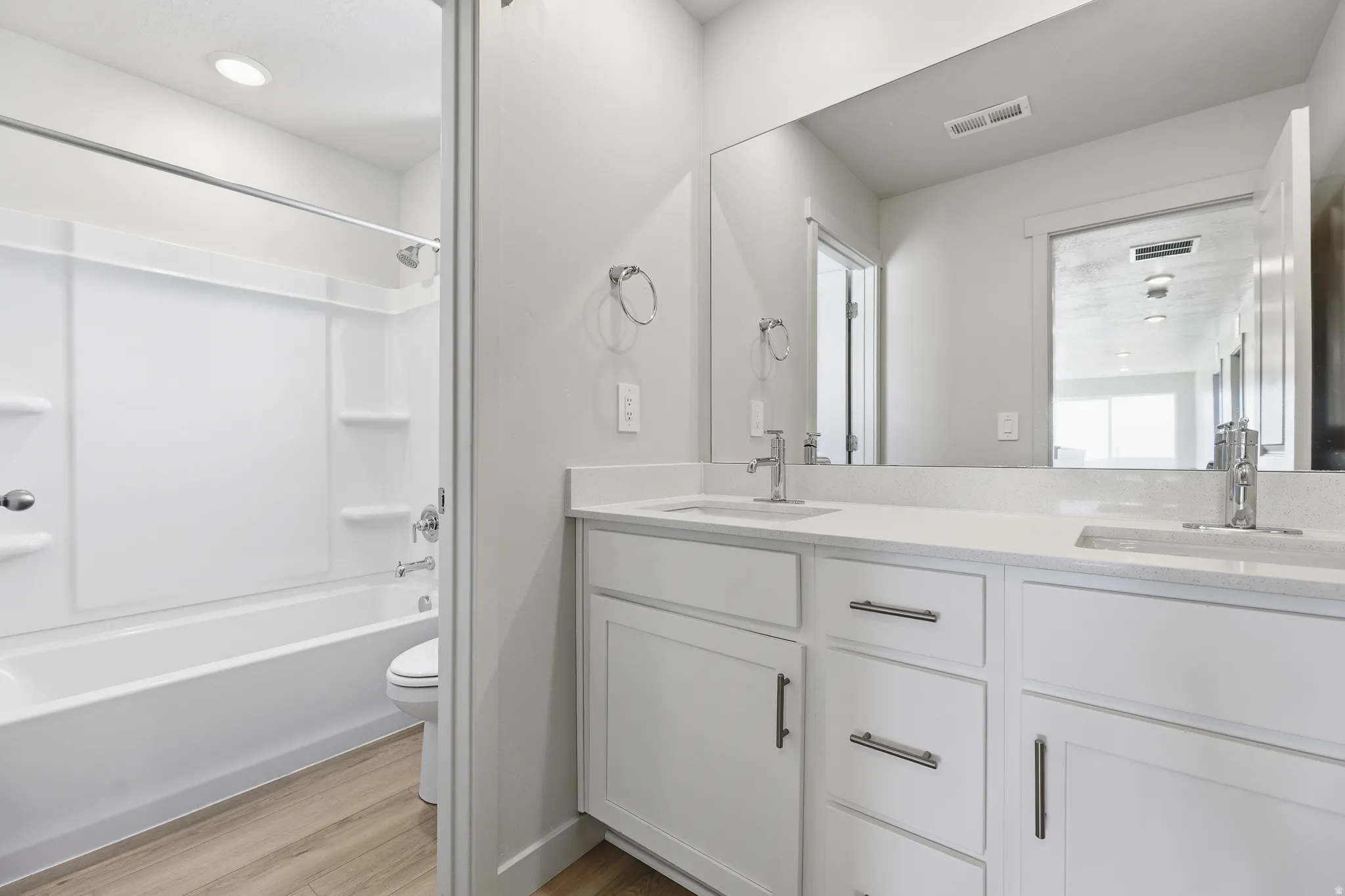 Double vanity with white cabinetry, polished chrome fixtures, and integrated sinks