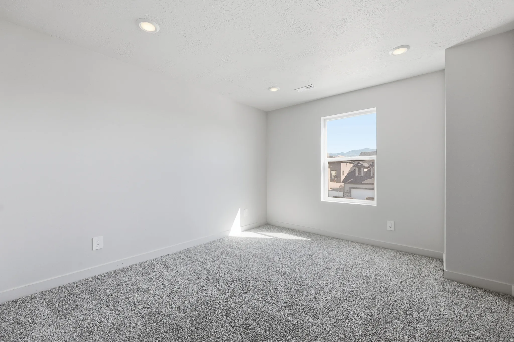 Recessed lighting fixtures, broad window, light gray wall finish, gray carpet flooring