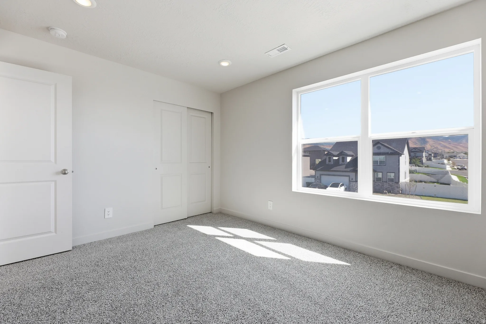 Recessed ceiling lighting, durable carpeting, two-panel interior door, bypass closet doors, and a large window